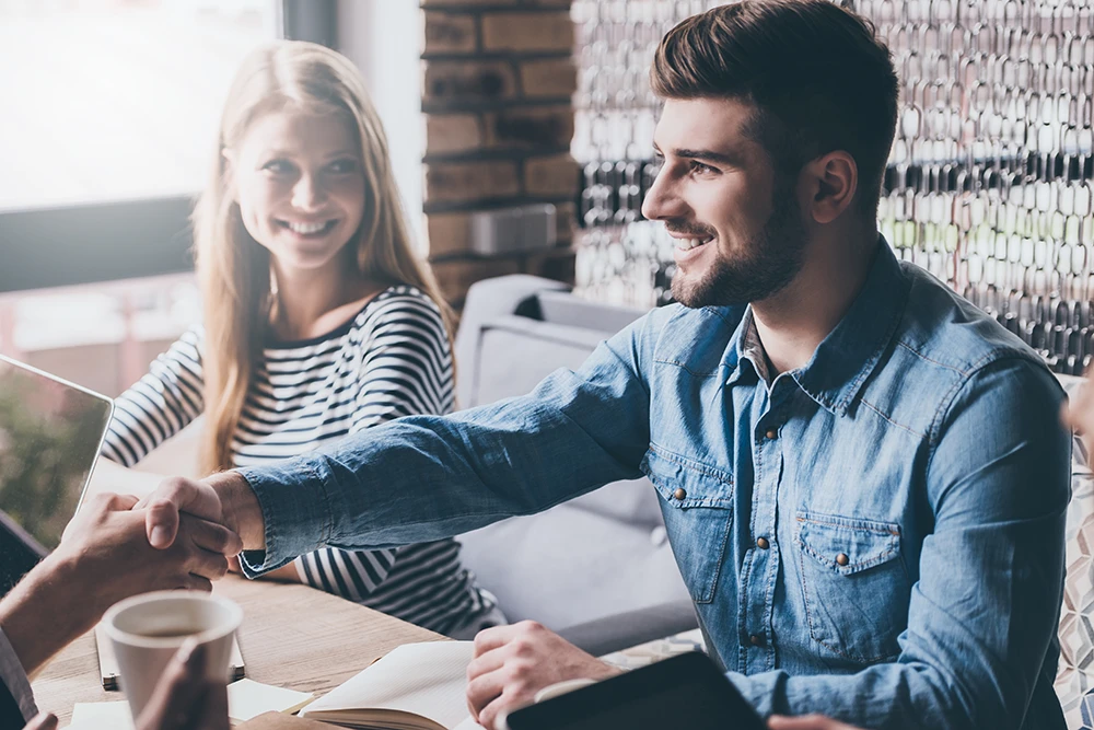 Business professionals shaking hands during a partnership discussion about payments and operations