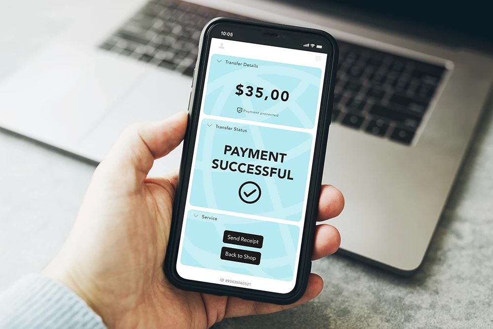 Business user entering payment details on a smartphone while holding a bank card